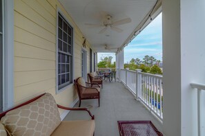 A covered porch with wicker furniture, a ceiling fan, and a view of the street.