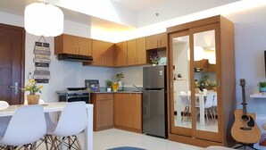 Une cuisine moderne avec des meubles en bois, un réfrigérateur en acier inoxydable et un coin repas avec des chaises et une table blanches.