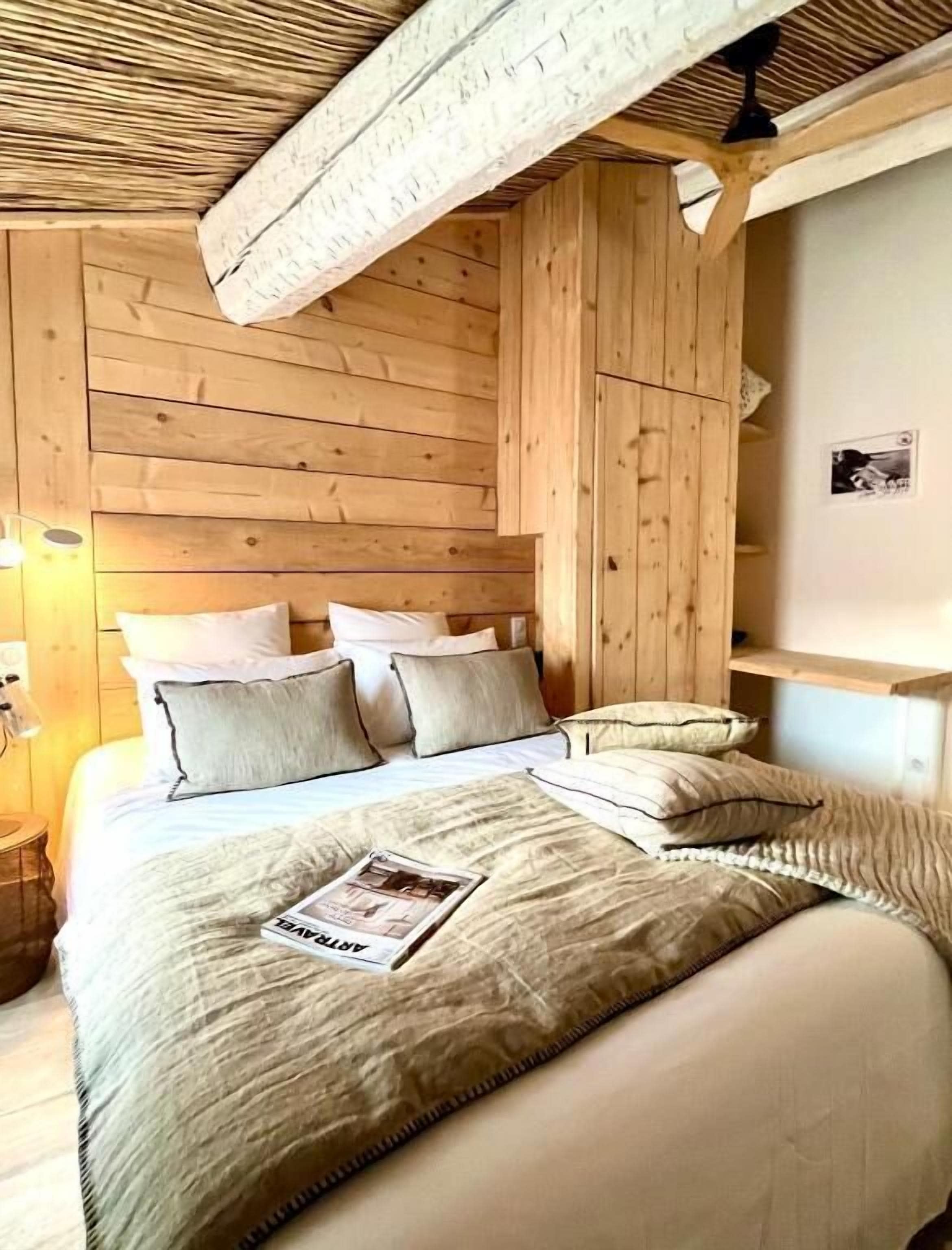 Une pièce en bois avec un lit, des oreillers et un magazine posé sur le lit.
