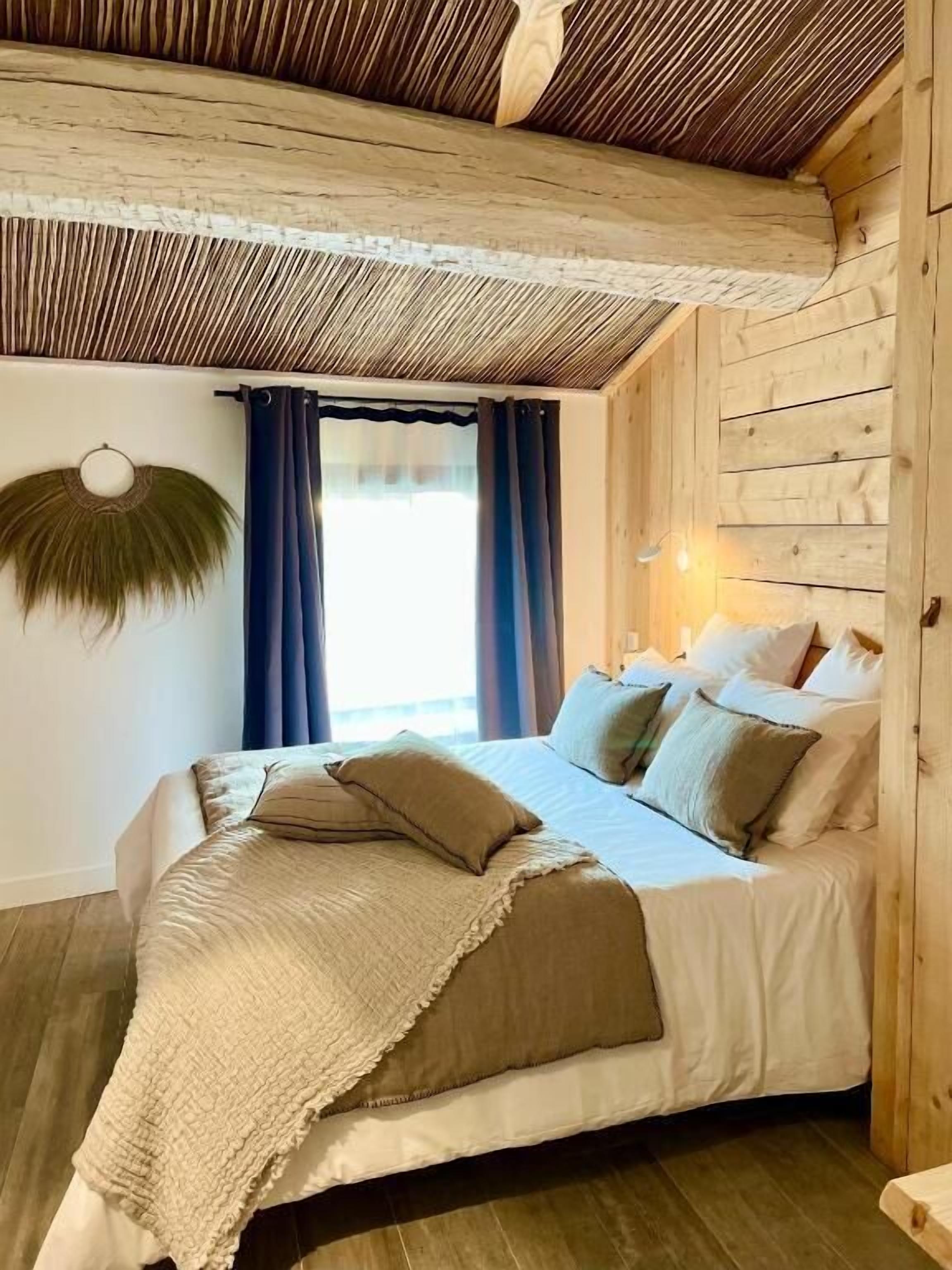 A wooden cabin-style bedroom with a bed, pillows, and a wall-mounted light fixture.