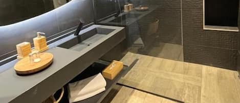 Un baño moderno con un espejo grande, paredes oscuras con textura y un tocador de madera.