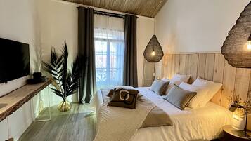 A bedroom with a bed, bedside table, lamp, and a television on a stand.