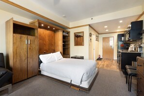 A bedroom with a bed, wooden wardrobe, and a kitchenette. - 2767 Slopeside Condo by RedAwning (Keystone)