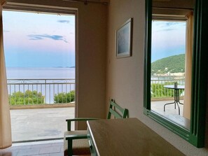 A room with a balcony overlooking a body of water and a distant landscape.