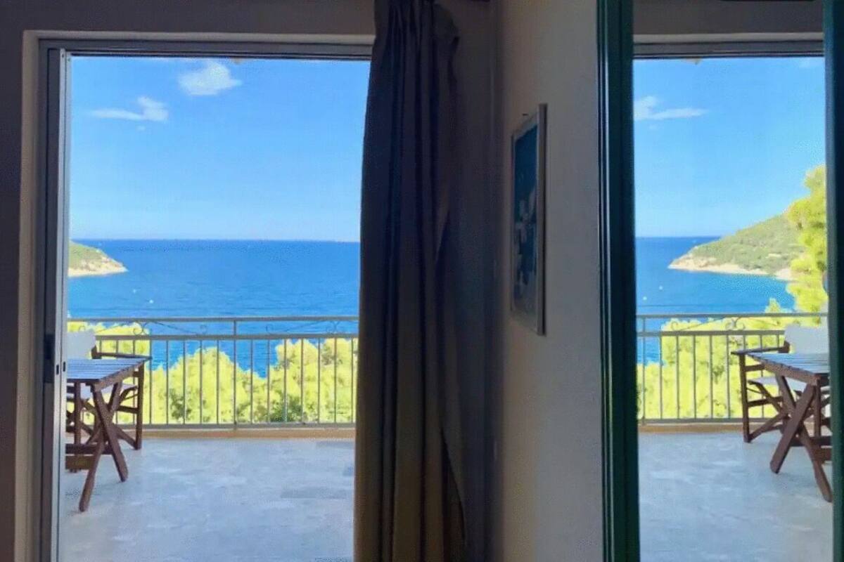 A balcony with a view of the sea and a grassy landscape.