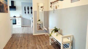 A hallway with a wooden floor, a white bench, a mirror, and a wall-mounted key rack.