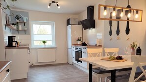 A modern kitchen with white cabinets, a built-in oven, and a dining area with a table set for two.