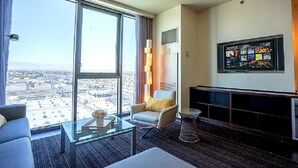 Ein modernes Hotelzimmer mit großem Fenster und Blick auf die Stadt, einem wandmontierten Flachbildfernseher und einer Sitzecke mit Glastisch.
