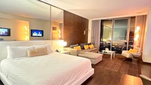 Ein modernes Hotelzimmer mit einem großen Bett, einer Couch, einem kleinen Tisch und einem Fernseher.
