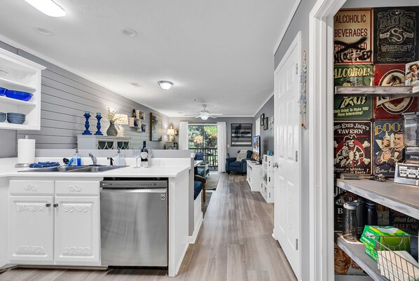 A modern kitchen with white cabinetry, a stainless steel dishwasher, and a central island. - Charming 2 Bed 2 Bath True Blue Pawleys Island Golf, 4 Pools Beach 5 min drive! (Pawleys Island)