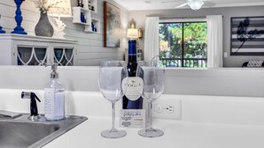 A kitchen counter with a wine bottle and two wine glasses, a sink, and a ceiling fan. - Charming 2 Bed 2 Bath True Blue Pawleys Island Golf, 4 Pools Beach 5 min drive! (Pawleys Island)