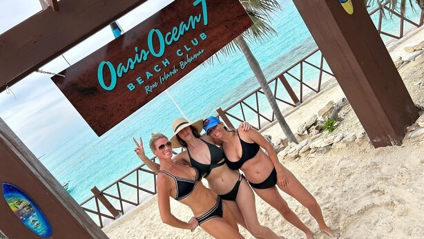 Letrero de un club de playa con vista al océano y palmeras.