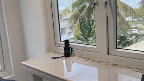 Una habitación con ventana que da a palmeras y un cielo despejado.