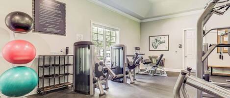 A fitness center with exercise equipment, a rack of weights, and exercise balls.