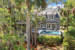 A large house with a swimming pool, surrounded by trees and greenery.