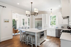 A spacious kitchen with a large island, stainless steel appliances, and white cabinetry.