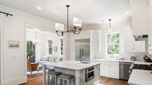 A spacious kitchen with a large island, stainless steel appliances, and white cabinetry.