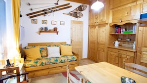 Ein gemütliches Zimmer mit einer Holzsofa, einem Tisch und einem Regal mit Büchern und einem Wasserkocher.