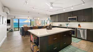 A modern kitchen with dark cabinets, stainless steel appliances, and a large island.