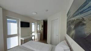 A hotel room with two beds, a large painting, a sink, and a mirror. - NEW! modern, high-quality, central apartment, sauna, garden, wallbox in Burhave (Butjadingen)