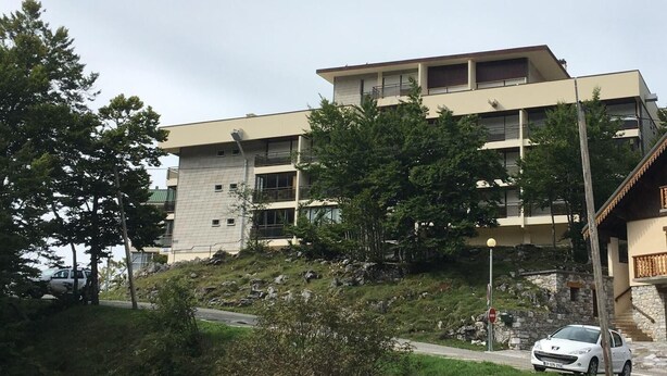 A multi-story building with a flat roof and a mix of window types.