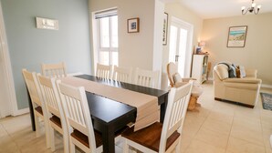 A dining area with a rectangular table and six chairs, a sofa, and a lamp in a living room.