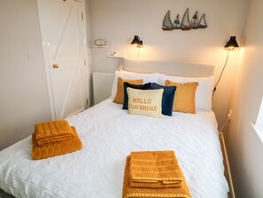 A neatly made bed with a white duvet, multiple pillows, and two folded towels.