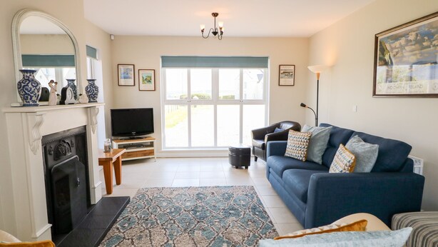 A living room with a fireplace, television, sofa, and a large window.