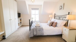 A bedroom with a bed, bedside table, lamp, and a chandelier.