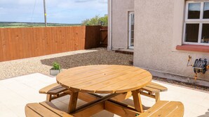 A wooden picnic table with benches in a backyard.