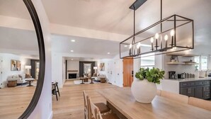A modern kitchen with a wooden countertop, a large vase with green plants, and a hanging light fixture. - @ Marbella Lane - Cozy Modern Home w/ Relaxing Design & Pool (Fullerton)