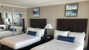 A hotel room with two beds, a large mirror, and artwork on the walls. - Ocean front - 6th Floor Caravelle Resort (Myrtle Beach)