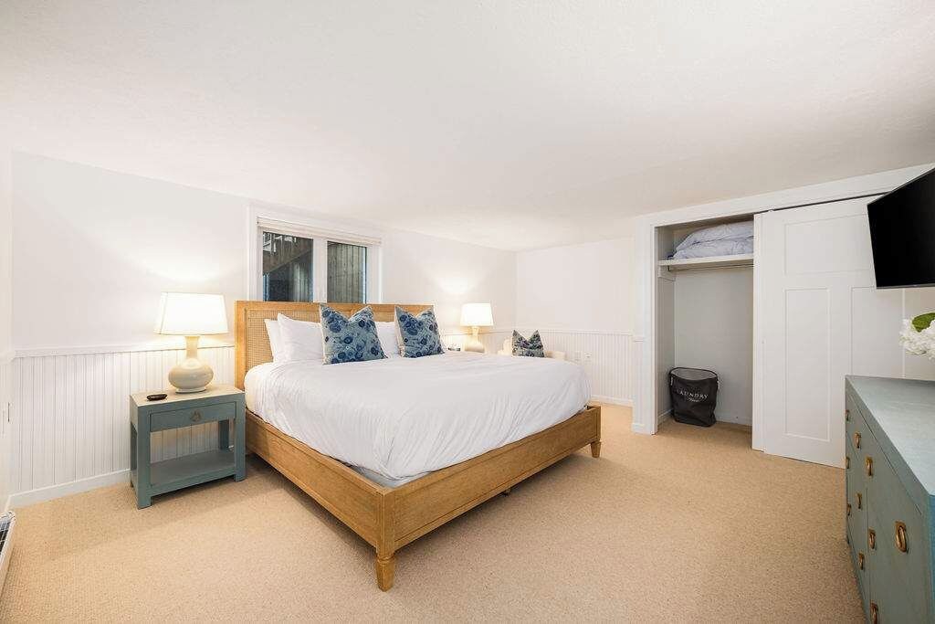 Une chambre à coucher avec un lit en bois, des lampes de chevet, une fenêtre et une armoire.