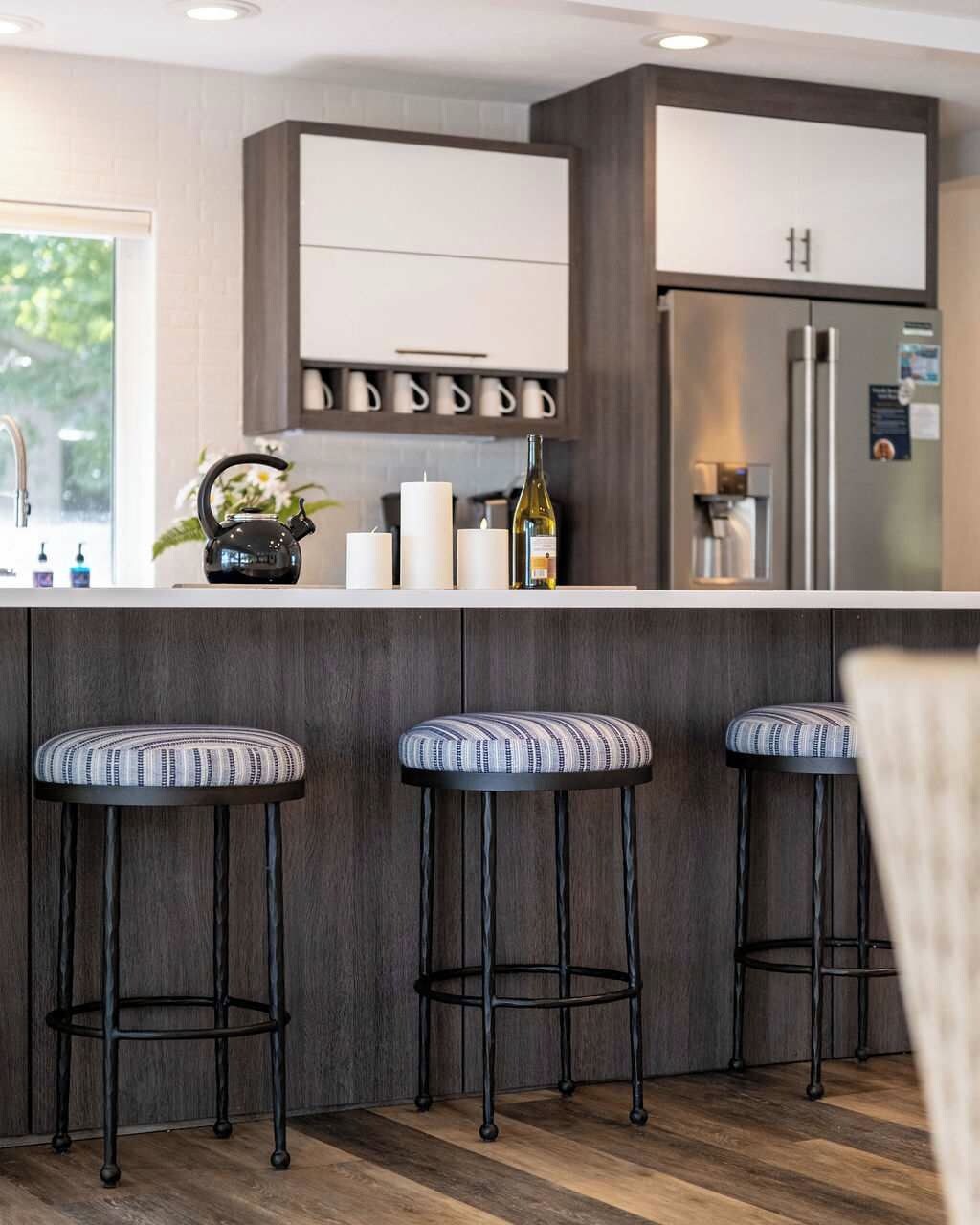 Een moderne keuken met een bar, roestvrijstalen apparatuur en barkrukken.