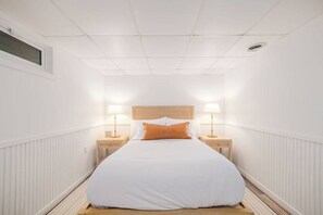 Een smalle hotelkamer met een eenpersoonsbed, twee nachtkastjes en een raam.