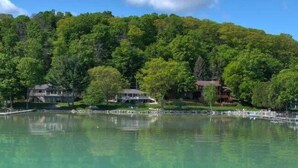 A lakeside property with multiple buildings surrounded by dense forest. - Big Glen Lakefront with Hot Tub and Two Fireplaces! (Glen Arbor)