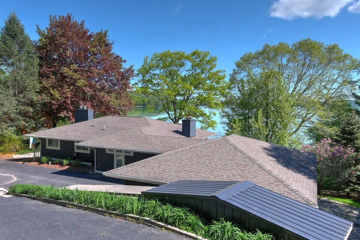 Une maison à deux étages avec un toit en pente, une cheminée et un garage.