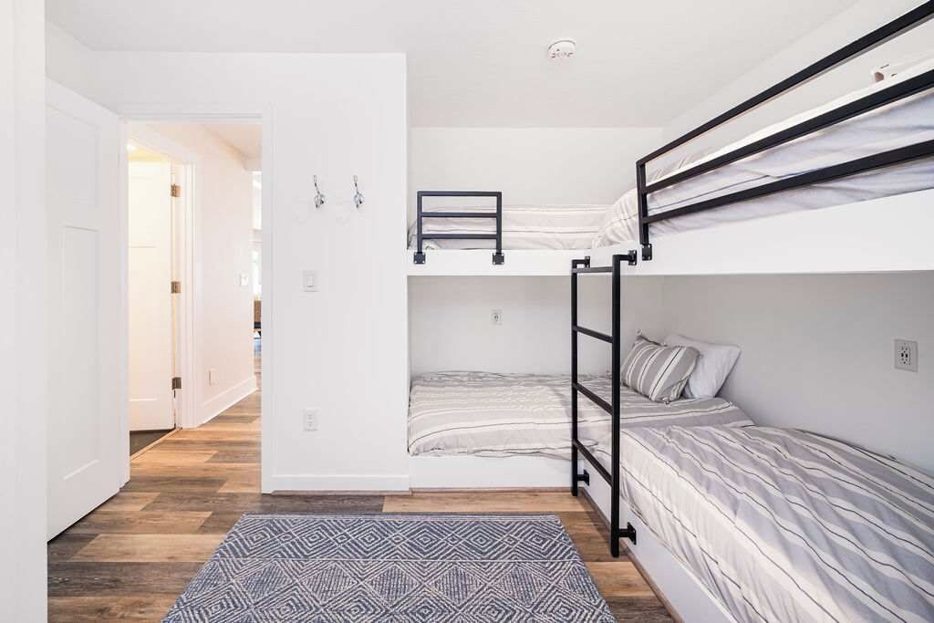 Una habitación compacta con literas, un tapete estampado y una puerta que da a otra zona.
