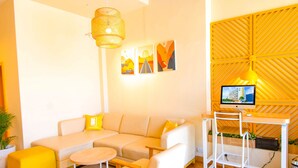 A modern living room with a sofa, a small round table, and a desk with a computer. - Bloom Hotel - Gachibowli (Hyderabad)