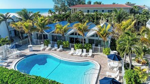 A resort with a swimming pool, lounge chairs, and a view of the ocean. - Coconuts101-BEACH FRONT COMPLEX-1BR ground level-ByIslandRealEstate (Holmes Beach)