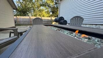 An outdoor patio with a long table, a barbecue grill, and a fish pond.