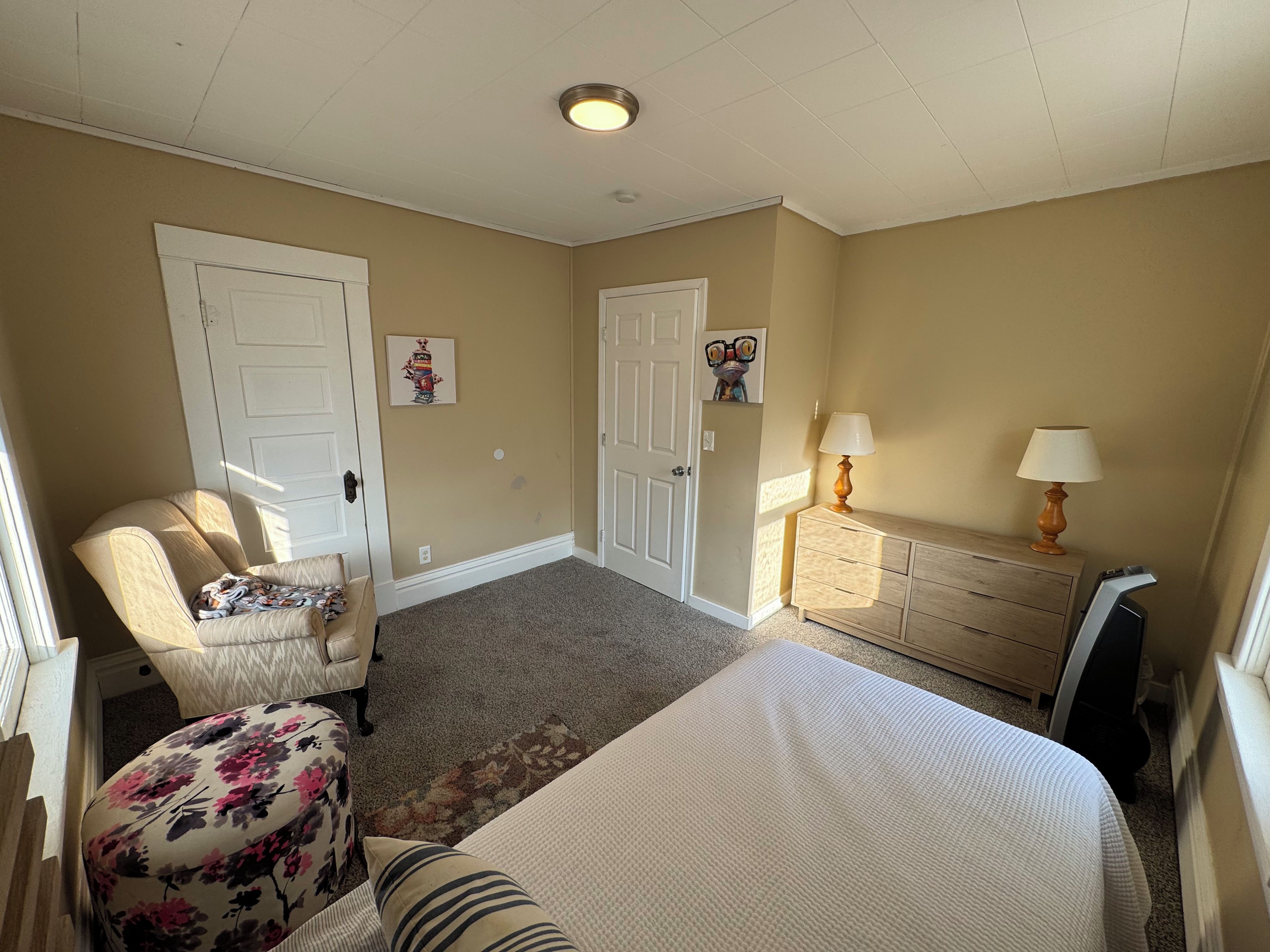 Une chambre à coucher avec un lit, une chaise, une commode et deux portes.