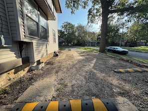A residential driveway with a house on the left, a tree on the right, and a parked car. - Kansas Escapes ,5BR, Pug Show  Dogs Welcome  Stormont Vail & I-70 (Topeka)