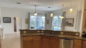 A kitchen with wooden cabinets, a stainless steel dishwasher, and pendant lighting. - Retreat at Genoa  (Port St. Lucie)