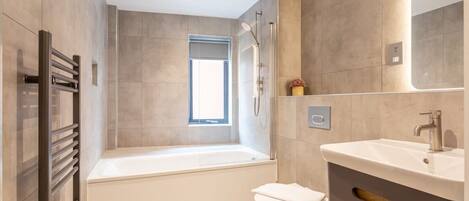 A modern bathroom with a bathtub, toilet, and vanity.