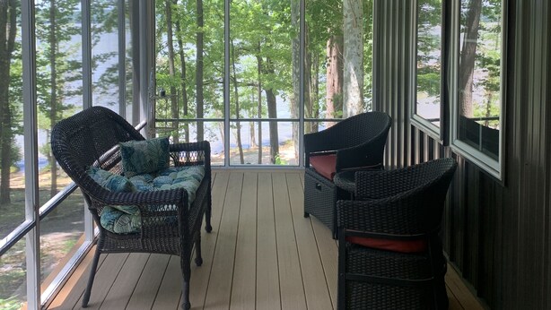 A covered porch with wicker furniture, large windows, and a ceiling fan. - Lake Front Cottage with private sandy beach (Cadiz)