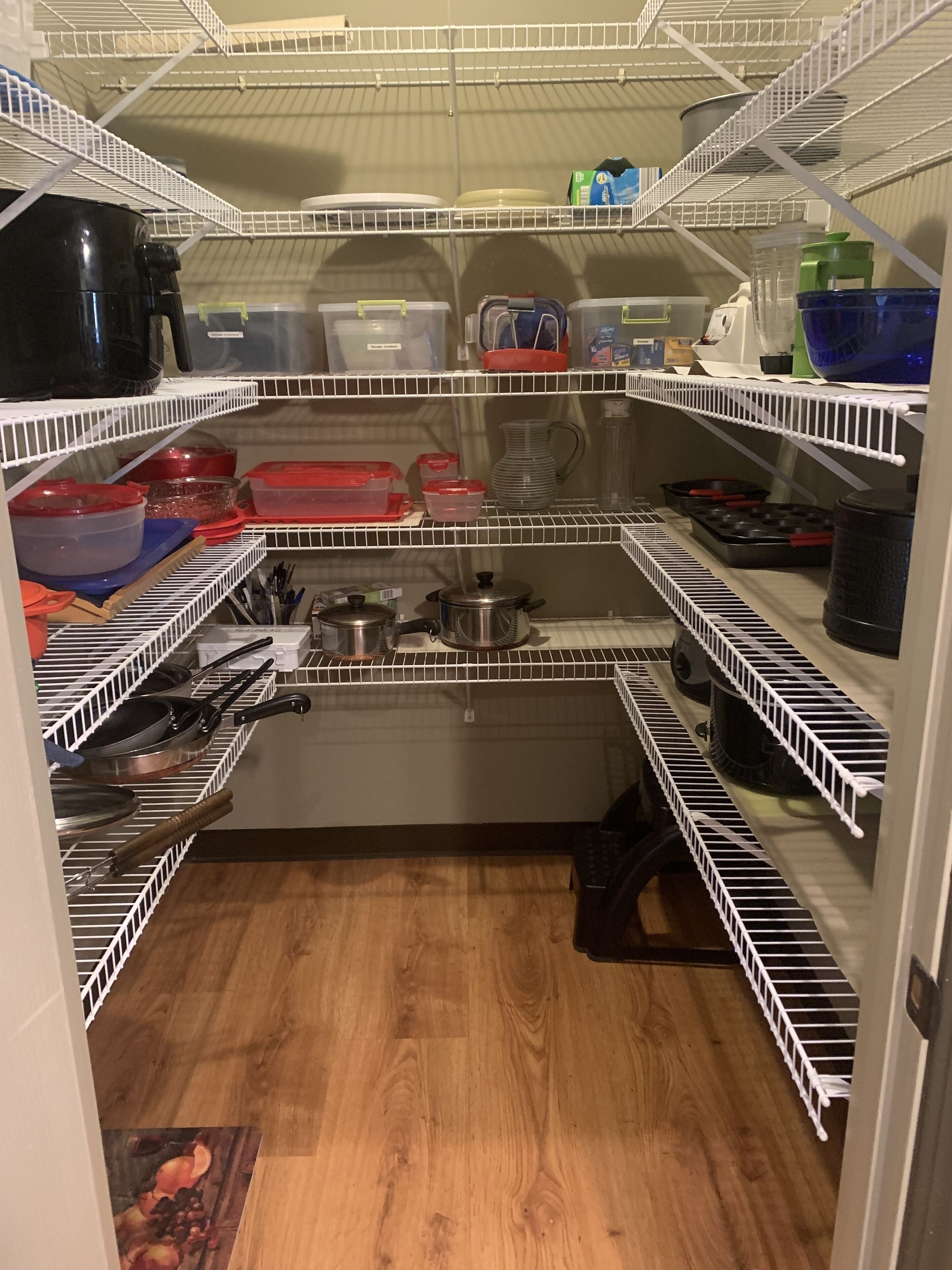 Una cocina con estantes de alambre blanco, diversos utensilios y recipientes.