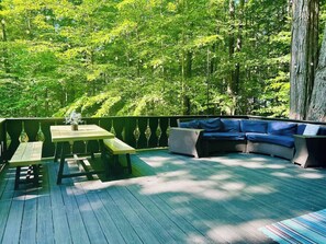An outdoor deck with a wooden table, benches, and a blue sofa.