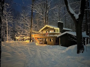 A snow-covered landscape with a lodge featuring a porch and a chimney.