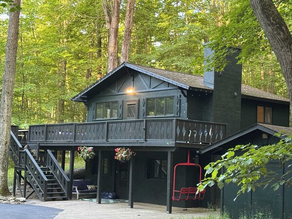 Une cabane avec un balcon, un escalier et une chaise rouge.